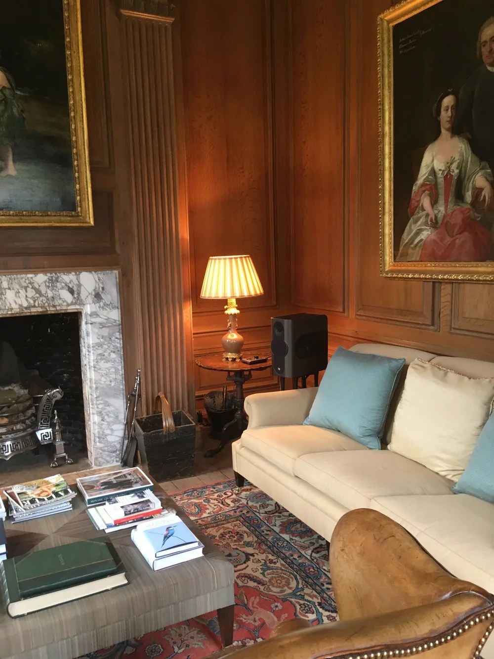 Restored wood-panelled drawing room with fireplace and oil paintings